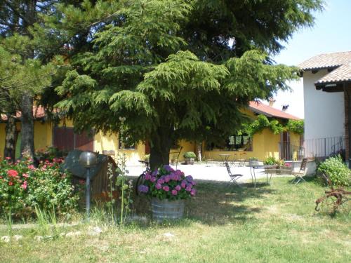 a tree in the yard of a house with flowers at Cascina La Maddalena Bed & Wine in Rocca Grimalda