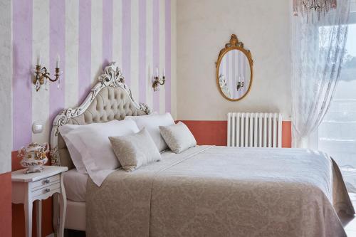 a bedroom with a large white bed with a mirror at La Zarabba Boutique Hotel in Ponti Sul Mincio