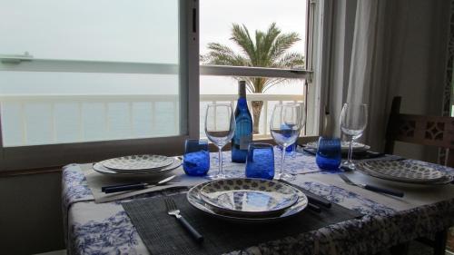 uma mesa com pratos e copos de vinho em Apartamento 1º linea playa Torrenueva, Motril, Granda em Torrenueva