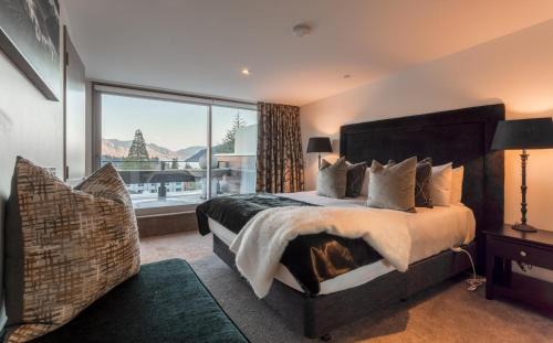 a bedroom with a large bed and a large window at Views on Hallenstein in Queenstown