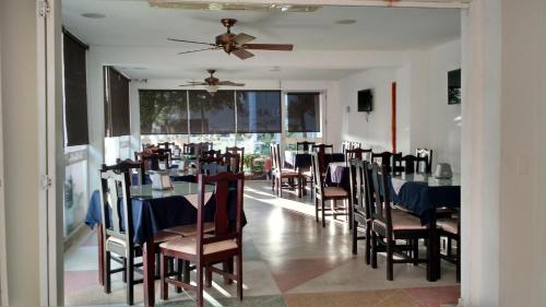 Hotel Bahia Plaza في سانتا مارتا: غرفة طعام مع طاولات وكراسي ومروحة سقف