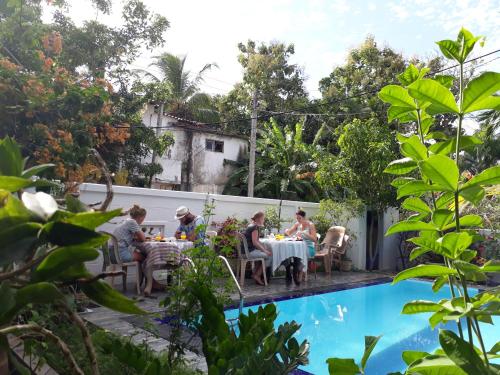 um grupo de pessoas sentadas à volta de uma mesa junto a uma piscina em Villu Villa em Anuradhapura