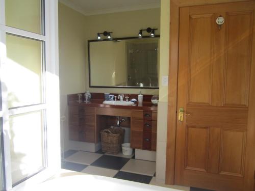 a bathroom with a sink and a mirror at Magnolia Cottage in Christchurch