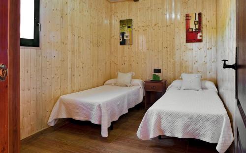 2 camas en una habitación con paredes de madera en Camping Carlos III en La Carlota
