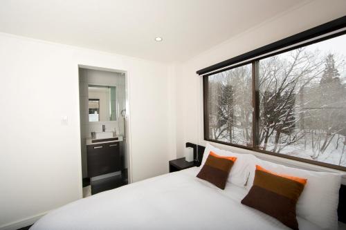 a bedroom with a bed and a large window at Sky Park Happo Chalet in Hakuba