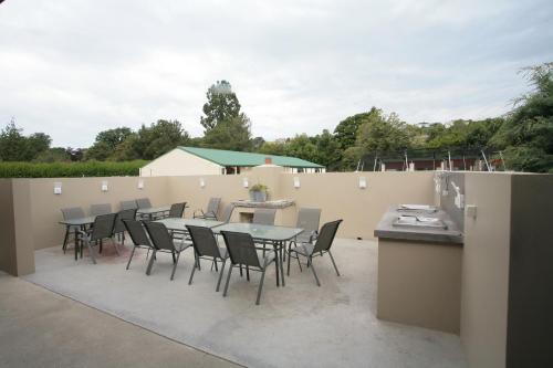 eine Terrasse mit einem Tisch, Stühlen und einem Zaun in der Unterkunft Oamaru TOP 10 Holiday Park in Oamaru