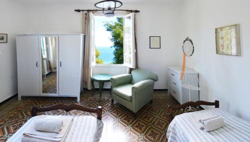 a bedroom with two beds and a chair and a window at Torre Alpicella - Holiday Home in Diano Marina