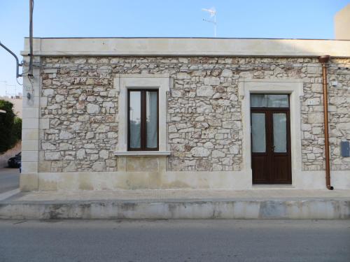 a stone building with two windows and a door at La casa di Bice in Cassibile