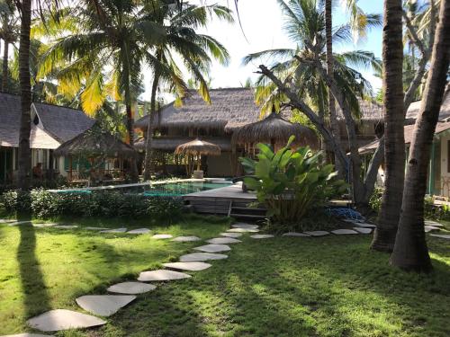a resort yard with a swimming pool and palm trees at Captain Coconuts Gili Air in Gili Air