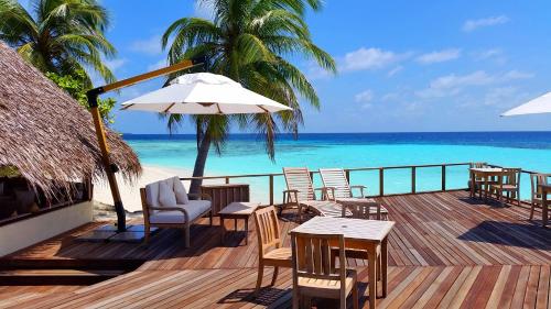 a patio area with chairs, tables and umbrellas at Makunudu Island in Makunudhoo