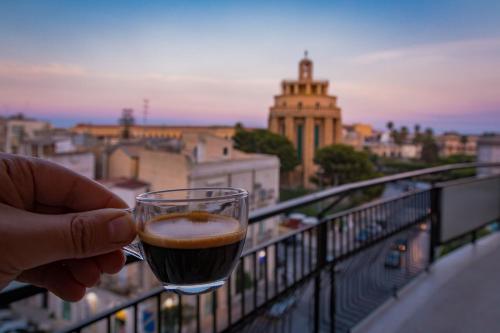 een persoon met een glas bier op een balkon bij PhotoGuest B&B in Siracusa