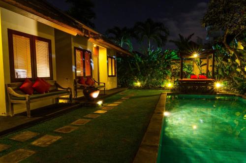 a swimming pool in front of a house at night at Imani Villas in Canggu