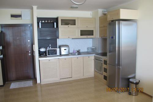 a kitchen with white cabinets and a stainless steel refrigerator at Black Sea Apartment in Nesebar