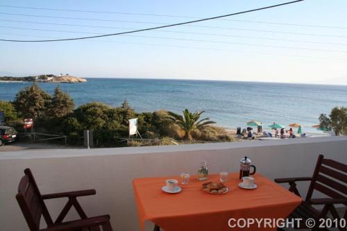 an orange table with chairs and a view of the beach at Margaritis Apartments in Agia Anna Naxos