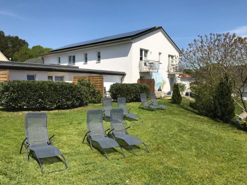 eine Reihe von Stühlen auf dem Rasen im Hof in der Unterkunft Gästehaus Schulz in Ahlbeck