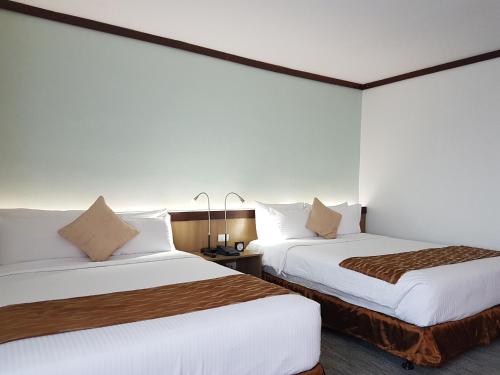2 camas en una habitación de hotel con paredes blancas en Dohera Hotel, en Cebú