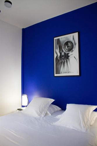 - un lit avec un mur bleu et une photo dans l'établissement Appartements de Jeanne, à Lille