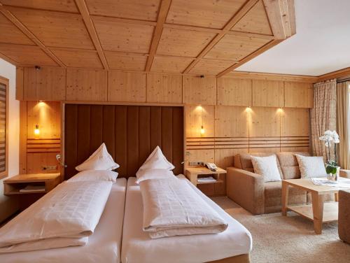 ein Hotelzimmer mit 2 Betten und einem Sofa in der Unterkunft Hotel Auriga in Lech am Arlberg