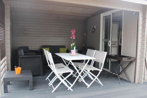 un patio avec une table et des chaises sur une terrasse dans l'établissement Gîte Fleur de Mer La Rochelle, à Puilboreau