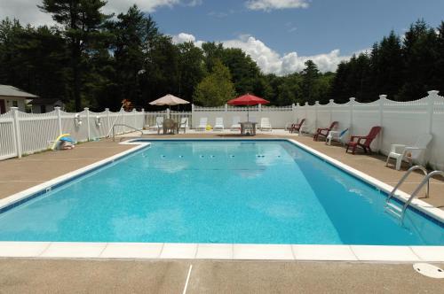 a swimming pool in a yard with a white fence at Saco River Motor Lodge & Suites in Center Conway