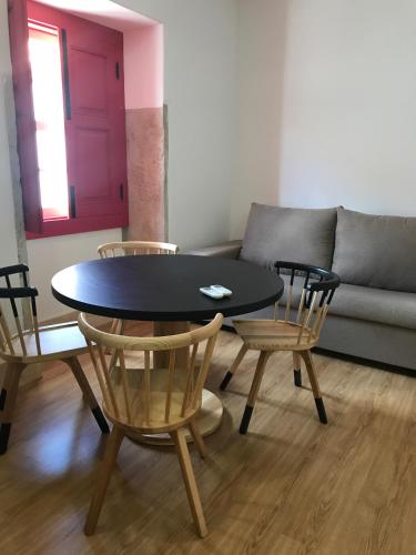 a table and chairs in a living room with a couch at Casa da Sé by PURUS in Coimbra