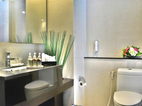 een badkamer met een toilet, een wastafel en een spiegel bij A-One Boutique Hotel in Bangkok