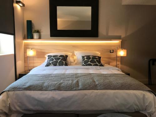 a bedroom with a large bed with a mirror above it at LOGIS Hotel-Restaurant Le Relais d'Aligre in Châteauneuf-en-Thymerais