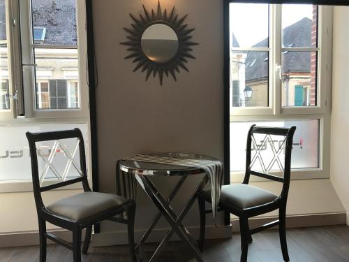 two chairs and a table and a mirror in a room at LOGIS Hotel-Restaurant Le Relais d'Aligre in Châteauneuf-en-Thymerais