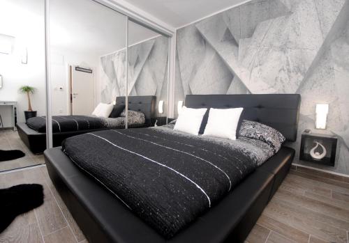 ein Schlafzimmer mit einem schwarzen Bett mit verspiegelten Wänden in der Unterkunft Apartments Kogo in Split