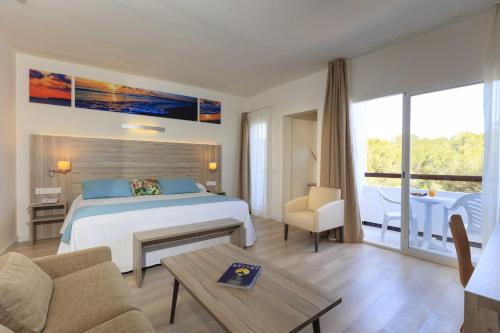 a hotel room with a bed and a table at Hotel Levante in Es Pujols