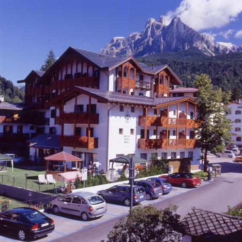 a large building with cars parked in a parking lot at Hotel Isolabella Wellness in Fiera di Primiero