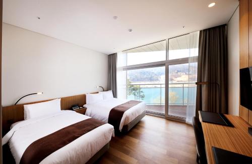 two beds in a hotel room with a large window at Midas Hotel & Resort in Gapyeong