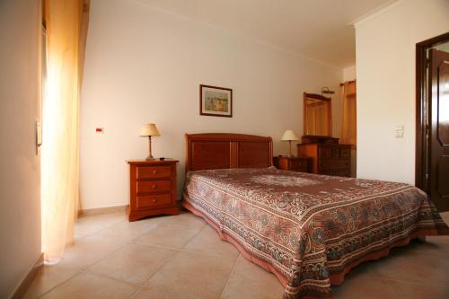 a bedroom with a bed and a dresser and a lamp at Apartamentos Coral do Vau in Portimão