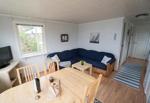 a living room with a blue couch and a table at Anfasteröd Gårdsvik - Örnnästet in Ljungskile