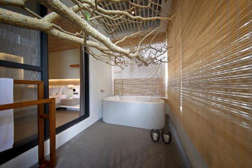 a bathroom with a tub and a tree branch on the wall at Laurel Villa B&B in Yuchi