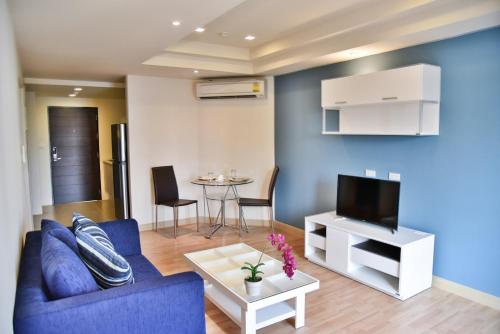 a living room with a blue couch and a tv at The Kaze 34 Hotel and Serviced Residence in Bangkok