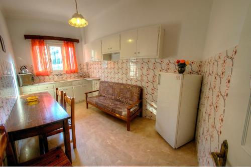a kitchen with a refrigerator and a table and a chair at Hotel Benitses Arches in Benitses