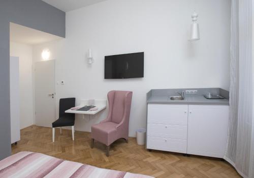 セゲドにあるDóm Apartmanのデスクとピンクの椅子が備わるホテルルームです。