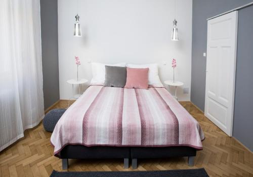a bedroom with a large bed with a pink blanket at Dóm Apartman in Szeged