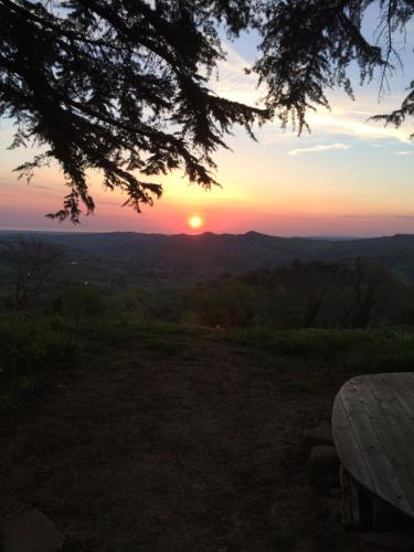 a sunset from the top of a hill with a picnic table at B&B Al Tardino in Sogliano al Rubicone