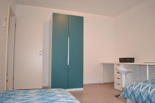 Schlafzimmer mit einem blauen Schrank und einem Schreibtisch in der Unterkunft Apartment Šik 1 in Koper