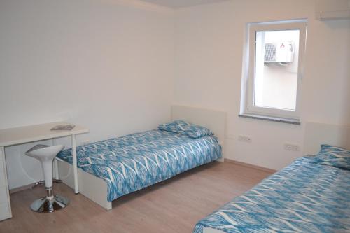 een kamer met 2 bedden, een bureau en een raam bij Apartment Šik 1 in Koper