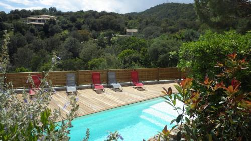een zwembad met stoelen op een houten terras bij La Villa faounzina in Favone