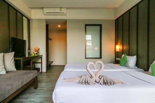two swans made out of towels sitting on a bed at La Lune Beach Resort in Ko Samed