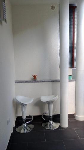 two white stools on a tile floor in a room at Apartment Šik 1 in Koper