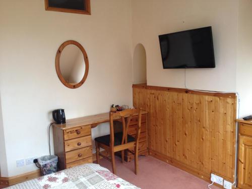 a bedroom with a desk and a television on the wall at Acorn Guest House in Oxford