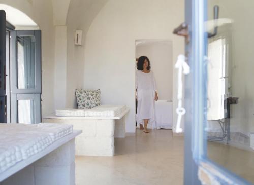 une femme en robe blanche debout dans une pièce dans l'établissement Masseria Eccellenza, à Pezze di Greco
