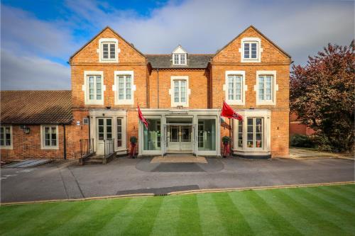 a large brick building with a lawn in front of it at Muthu Clumber Park Hotel and Spa in Worksop