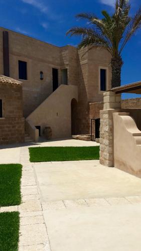 a house with a palm tree in front of it at Il Baglio sull'Acqua in Favignana