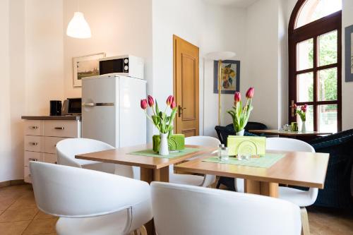 eine Küche und ein Esszimmer mit Tischen und weißen Stühlen in der Unterkunft Pension an der Pillnitzer Schlossfähre in Dresden